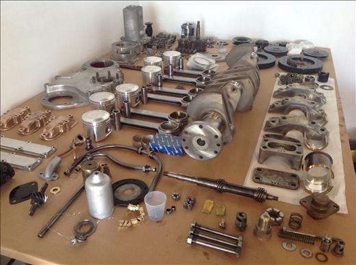 Moteur démonté : pistons, vilebrequin et pièces alignés sur l'établi
